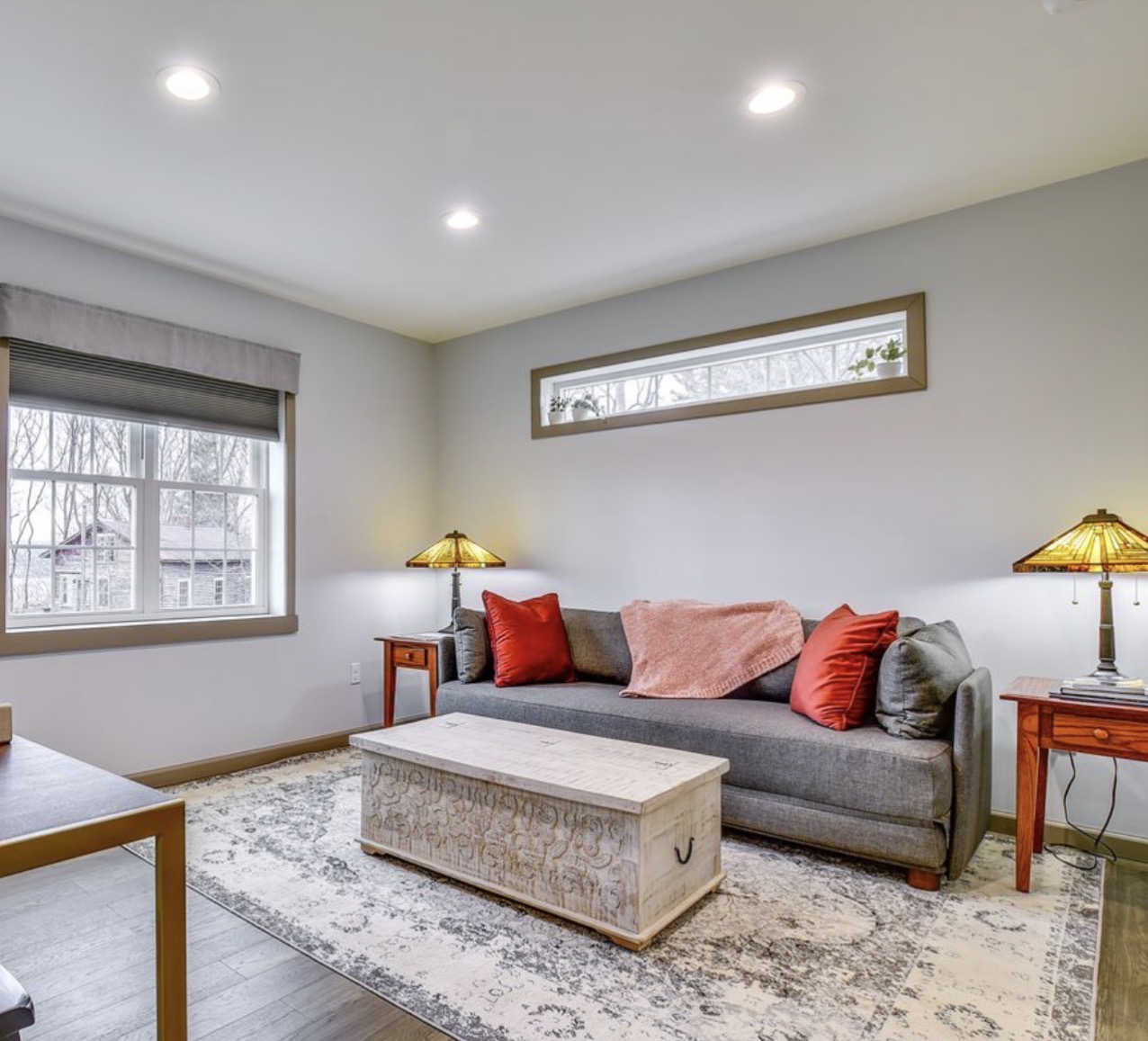 Living area with grey queen sleeper sofa, coffee table, area rug and stained glass lamps