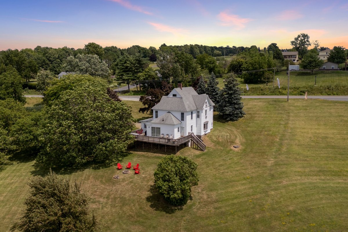 The house with a lakeside fire pit and red Adirondack chairs on the lawn