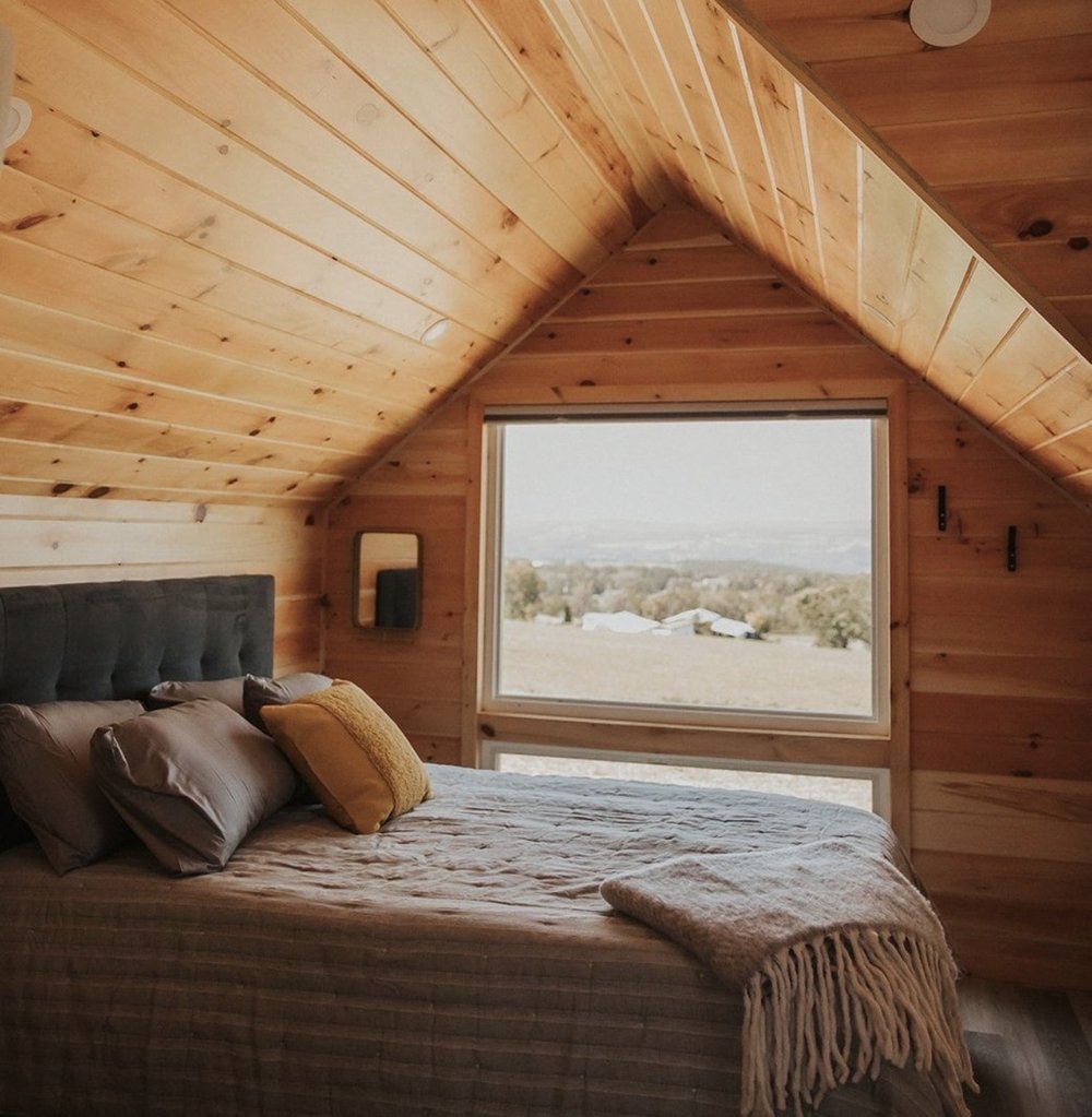 The micro-cabin bed beneath a picture window over the farmland