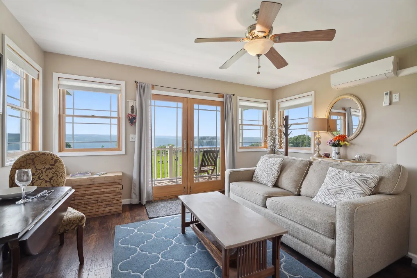 Villa living room with sofa bed, dining table, and French doors opening to a deck overlooking Seneca Lake