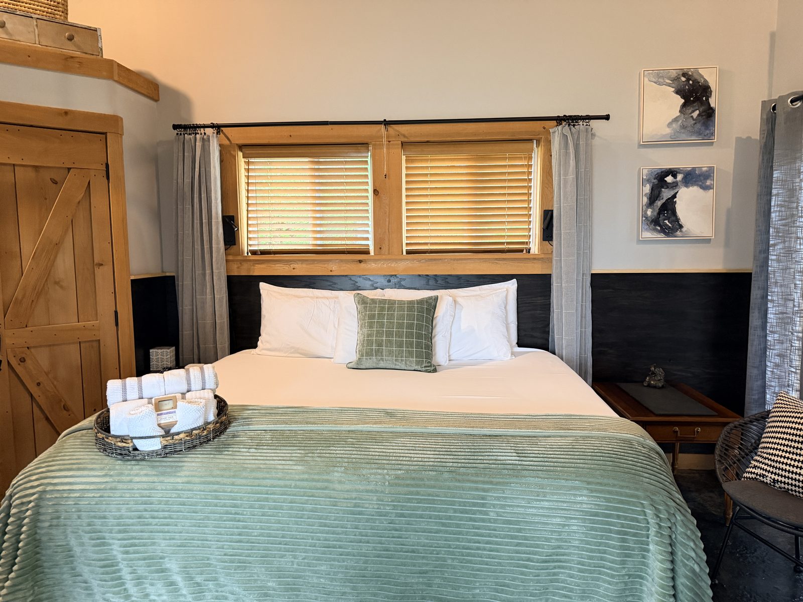 EcoBarn bedroom with king bed, reclaimed wood window frame, sliding barn door and green throw