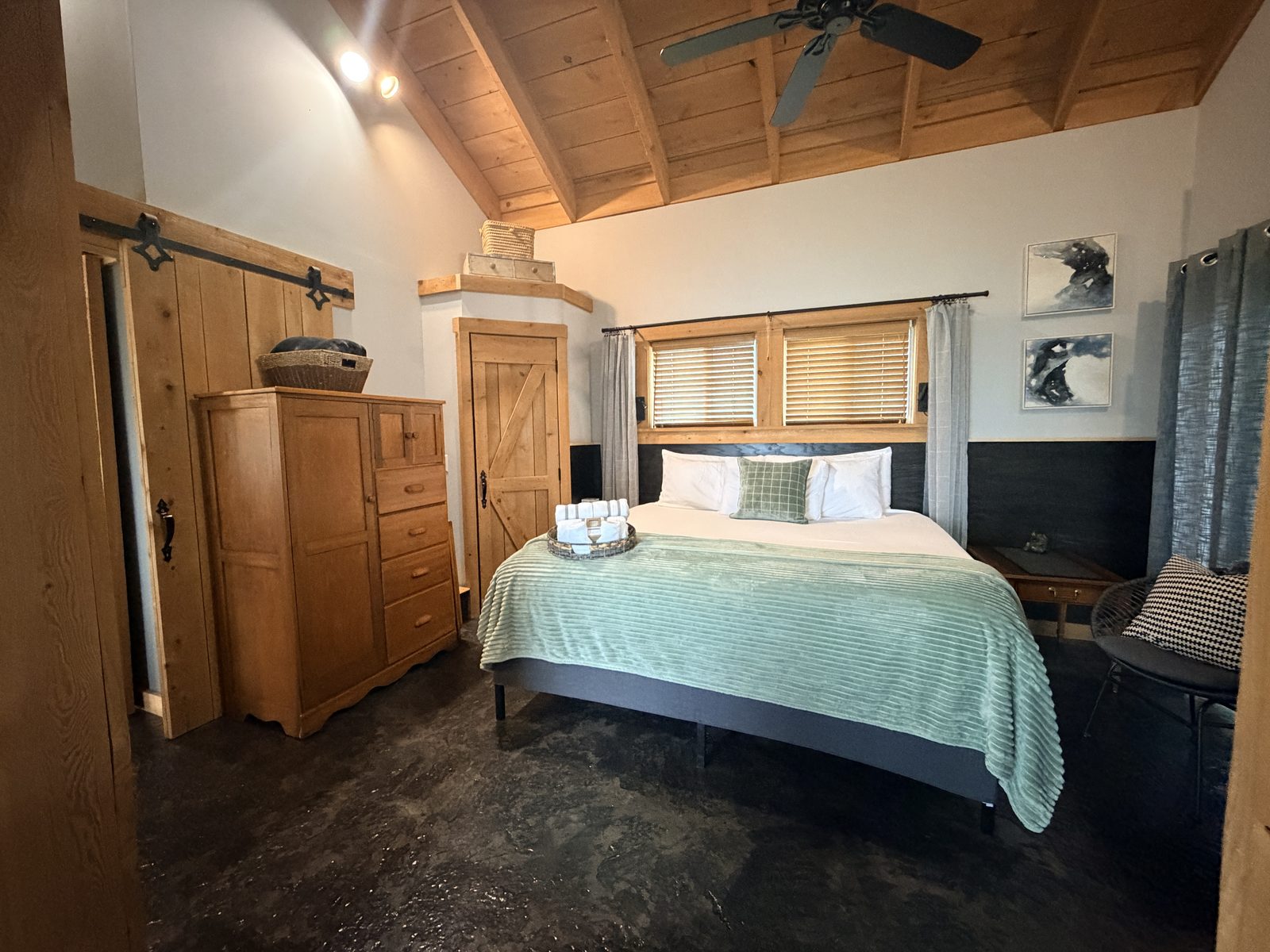 Bedroom with king bed, vaulted wood ceiling, antique wardrobe and sliding barn door
