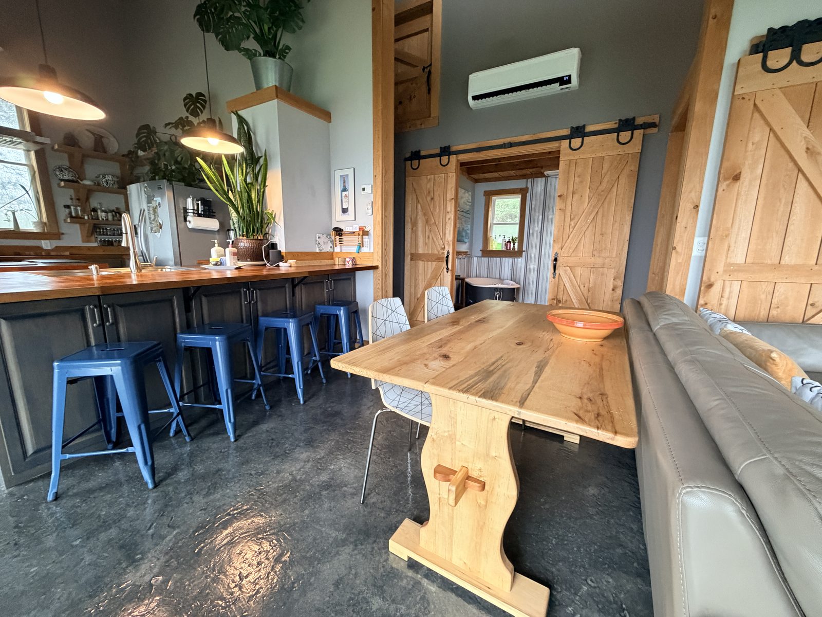 Trestle dining table and breakfast bar with stools, barn doors open to the clawfoot tub room beyond