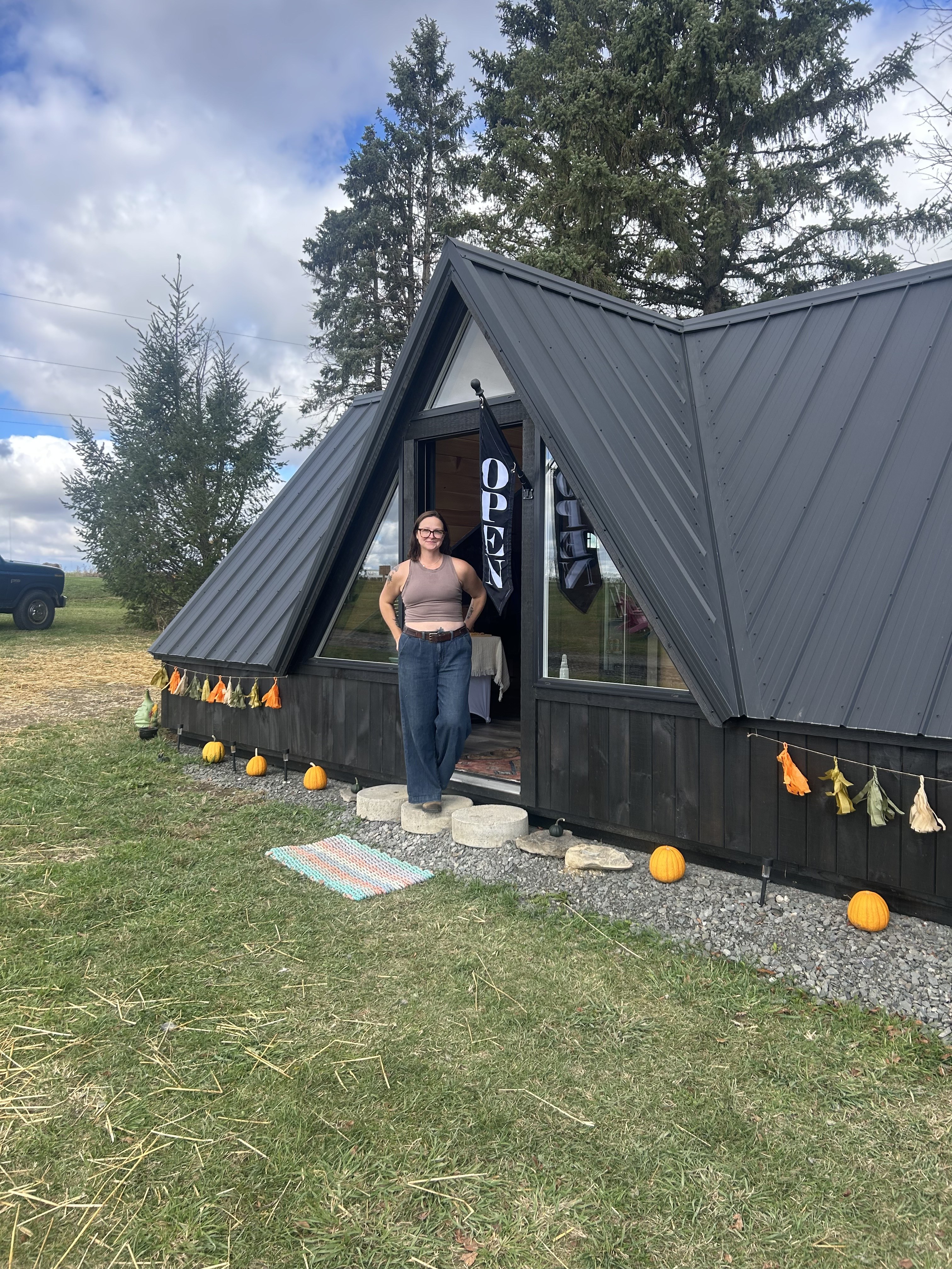 Tamarack Ridge Farm black A-frame farm store with OPEN flag and pumpkins